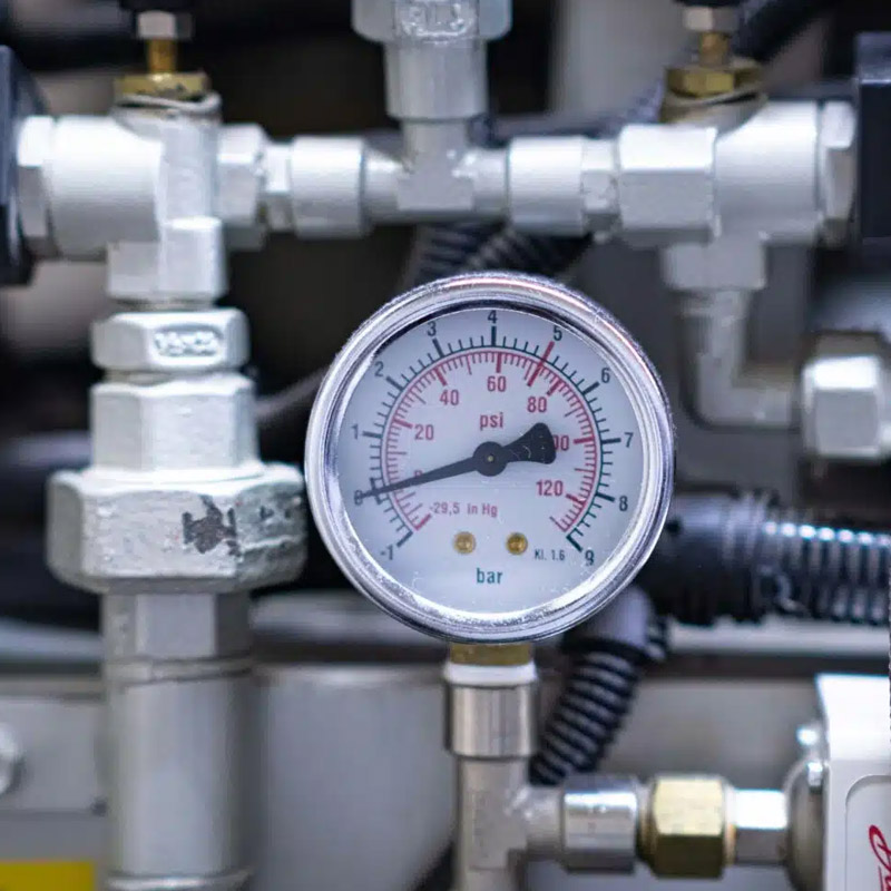 Industrial pressure gauge measuring bar and psi in valve system.